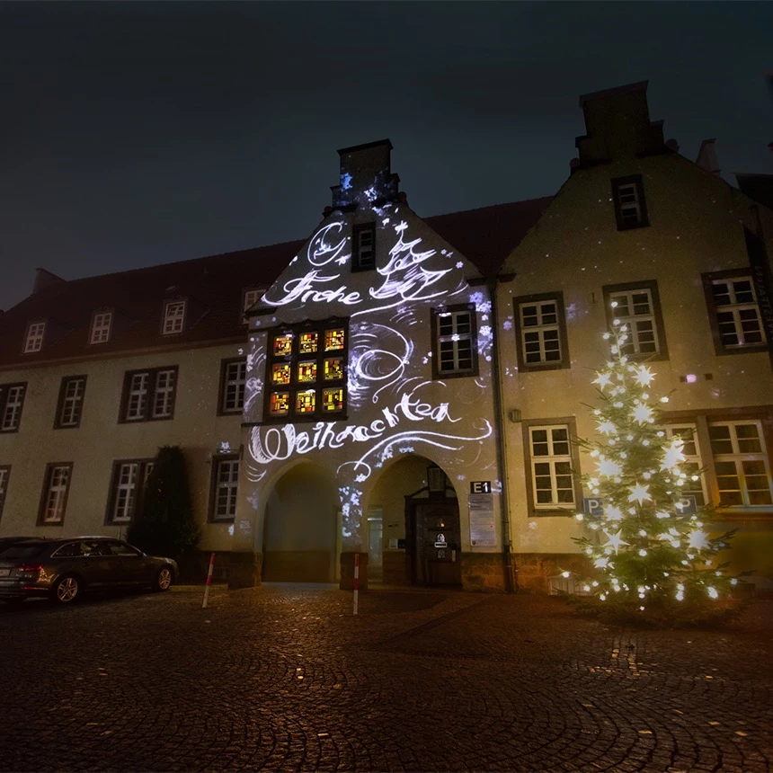 Weihnachtsgrüße bei Projektionsshow auf Rathaus-Fassade in Halle Westfalen dargestellt