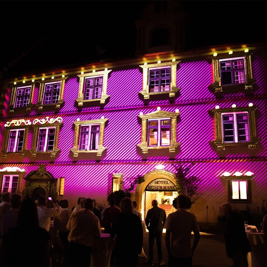 Grafische Hervorhebung der Gebäudenstrukturen in pink und gold bei gebäudeindividueller Fassadenprojektion am Schloss Weitenburg für ein Charity Event
