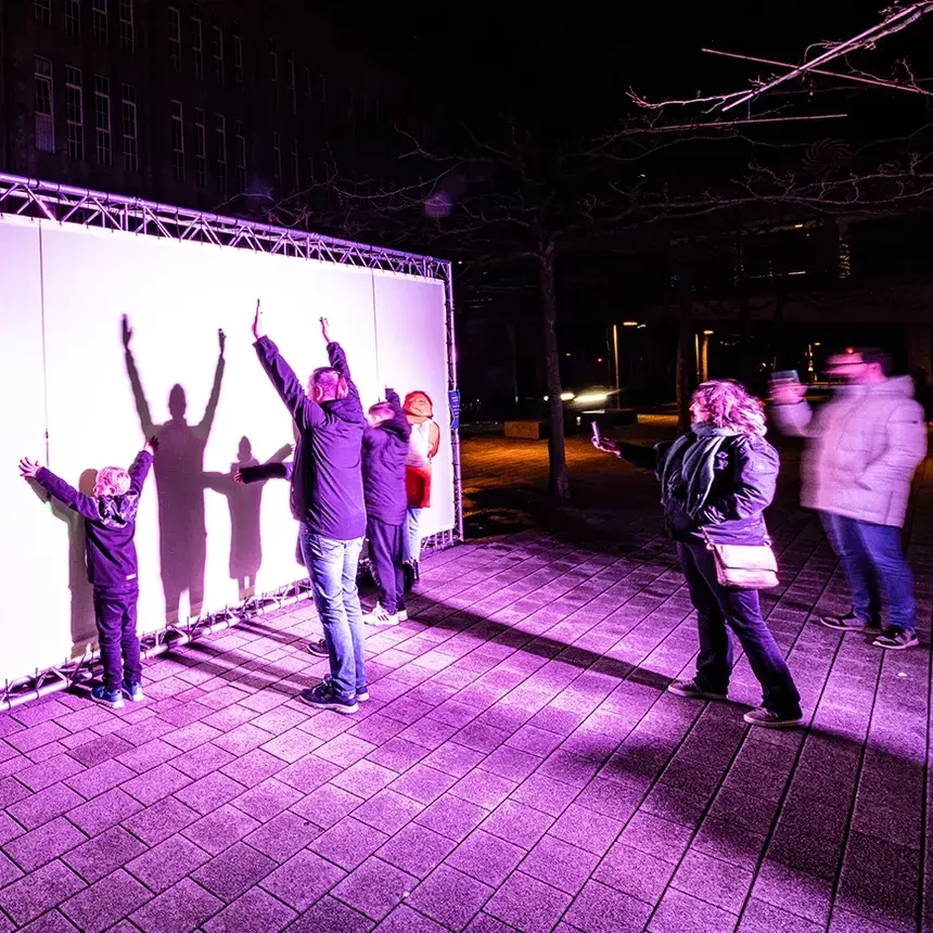 Eine Familie spielt mit Licht und Schatten vor einer Schattenwand