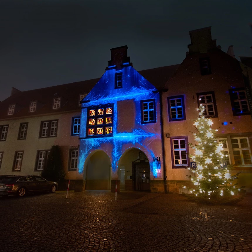 3D Video Mapping erweckt den Eindruck die Gebäudefassade des Rathauses in Halles Westfalen würde plötzlich einfrieren, virtuelle Eiskristalle in blau erscheinen