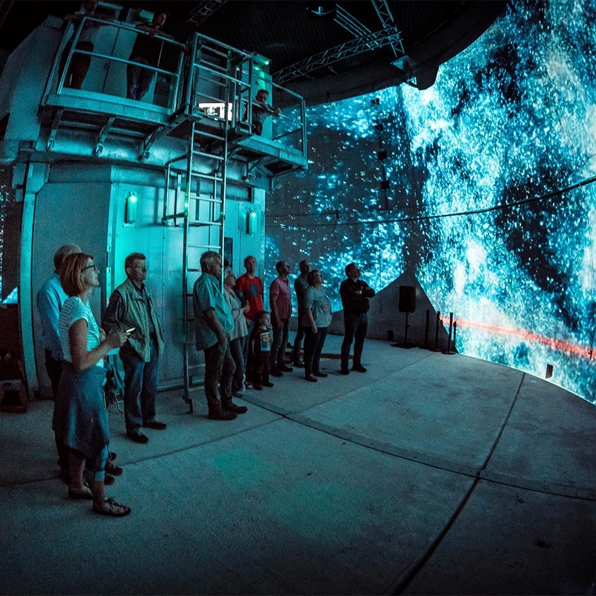 Zuschauer betrachten 360° Mapping in einer Windkraftanlage mit Projektionen vom Weltall