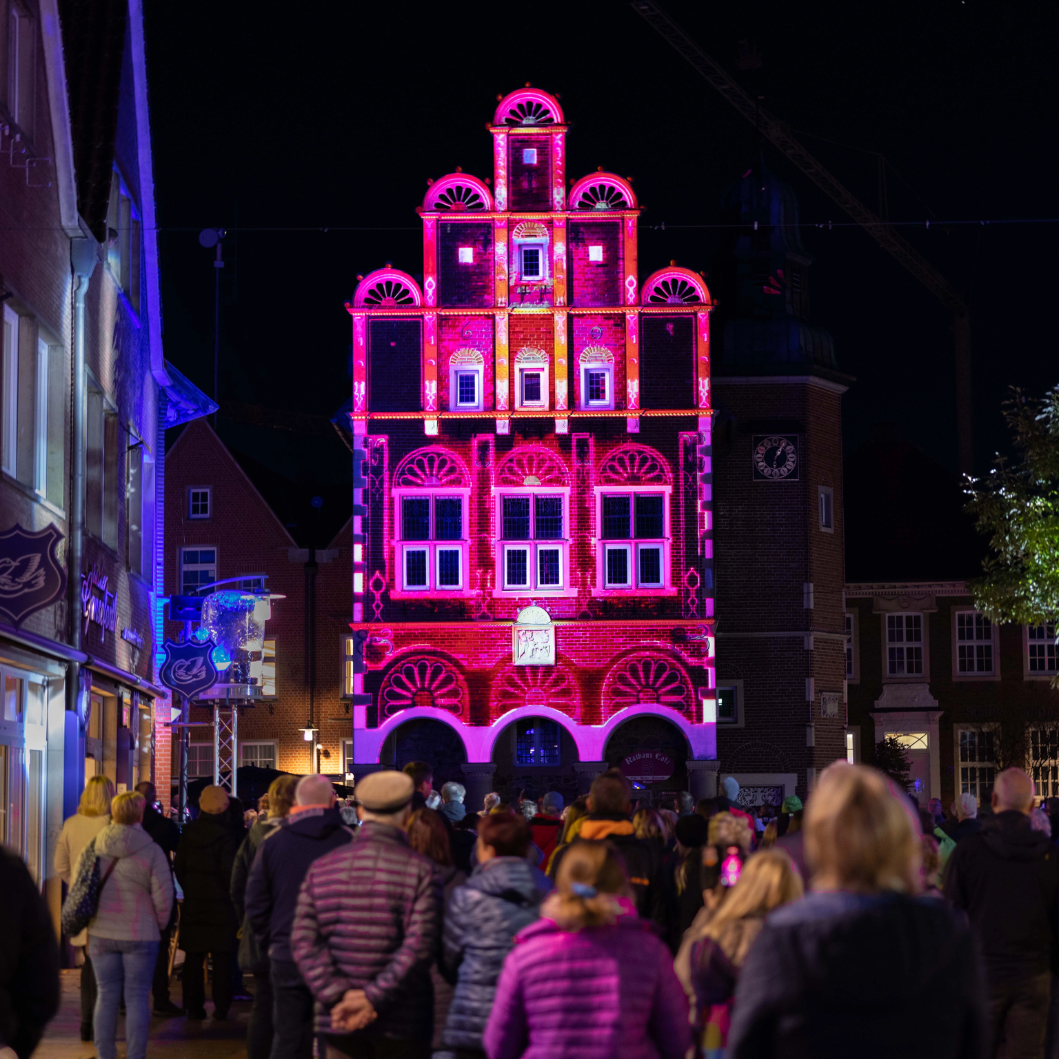 3D Video Projektion auf historisches Rathaus in Meppen bei dem die Gebäudestrukturen wie Fachwerk und Ornamente in pink hervorgehoben sind
