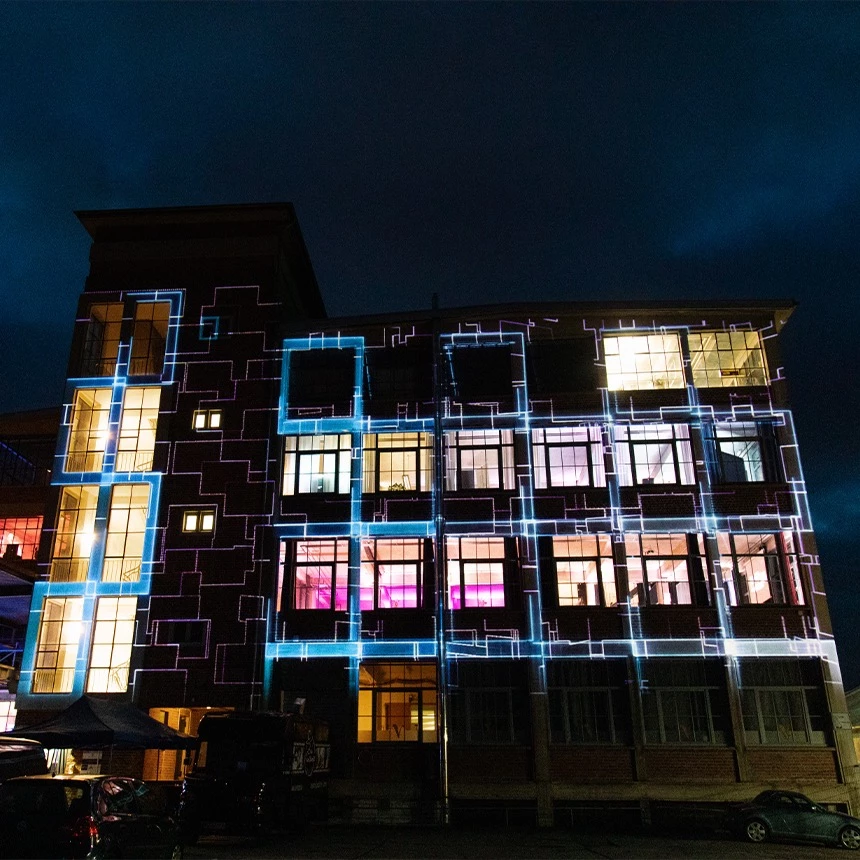 Video projection on a historic factory facade, the structure of which was emphasized by purple effects