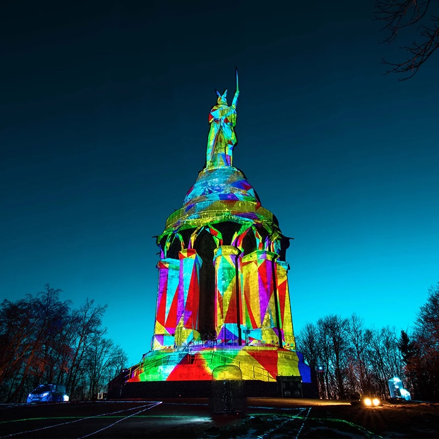A projection mapping for the light festival The Hermann shines shows object-specific effects on the Hermann monument, here the statue appears covered with colorful geometric shapes