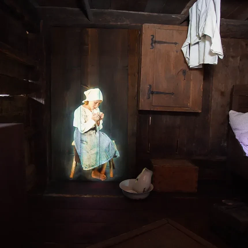 Holo-Projektion einer Magd in altertümlichem Kleid in historischer Kulisse
