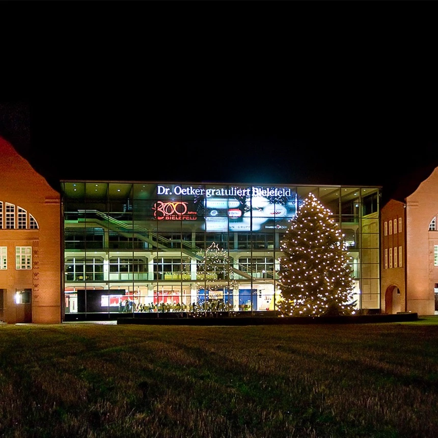Architectural illumination on a cubist glass facade of Dr. Oetker shows product information and brand messages via video projections