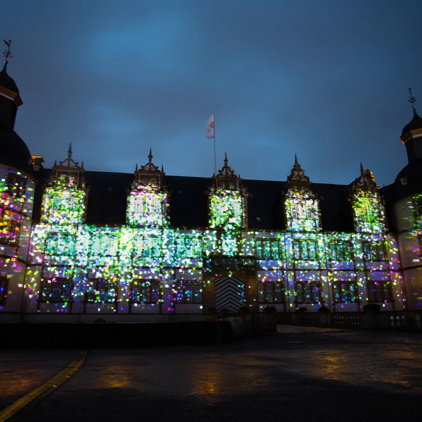 3D Projektion zeigt im großen Finale buntes Konfetti, das sich virtuell auf der Schloss-Fassade ausbreitet