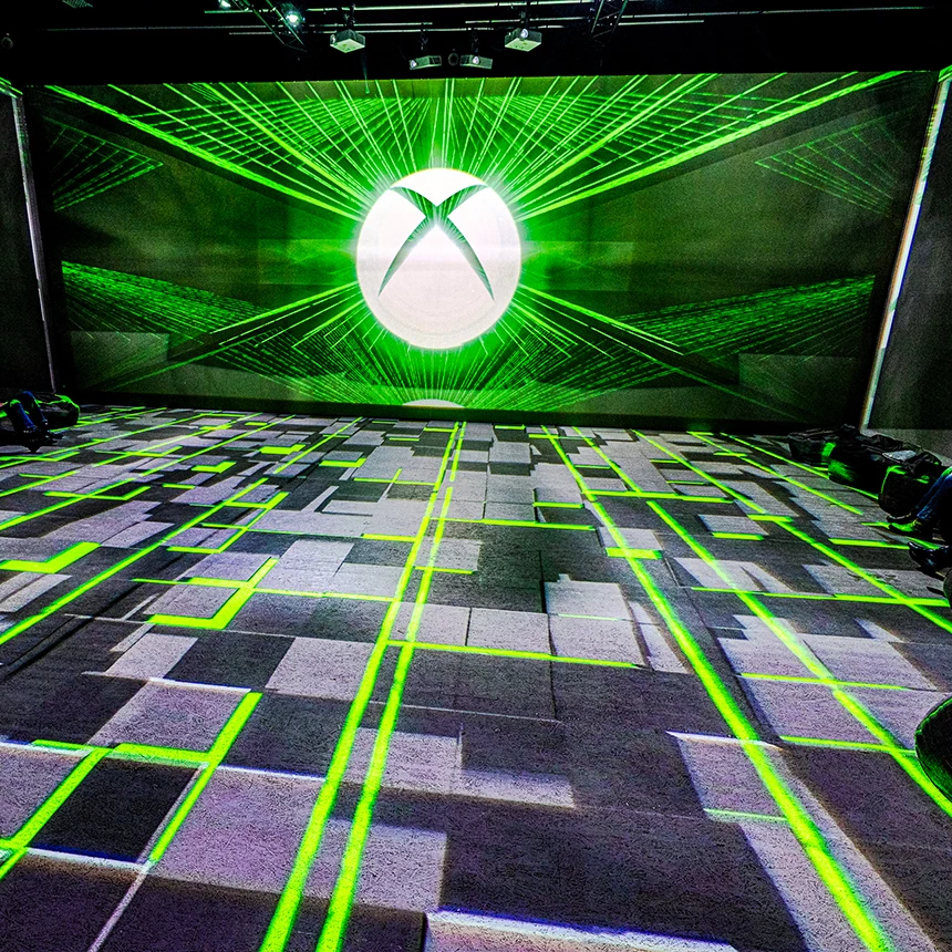 Geometrische Formen werden auf auf den Boden projiziert, während an der Wand das Xbox Logo zu sehen ist