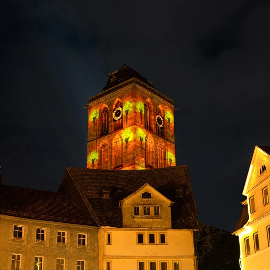 Stimmungsvoll erleuchtete Innenstadt mit Video-Projektion auf 2 Seiten des Kirchturms in Bad Hersfeld
