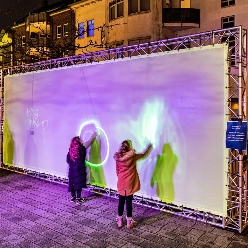 Children play with a shadow wall on which they can paint with light using special pens
