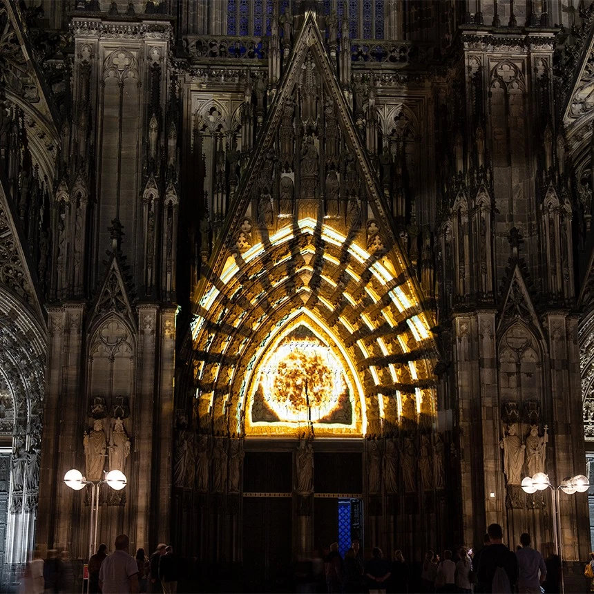 Ein Projektion Mapping auf das Domportal des Kölner Doms zeichnet die Gebäudestrukturen mit goldenem Licht nach