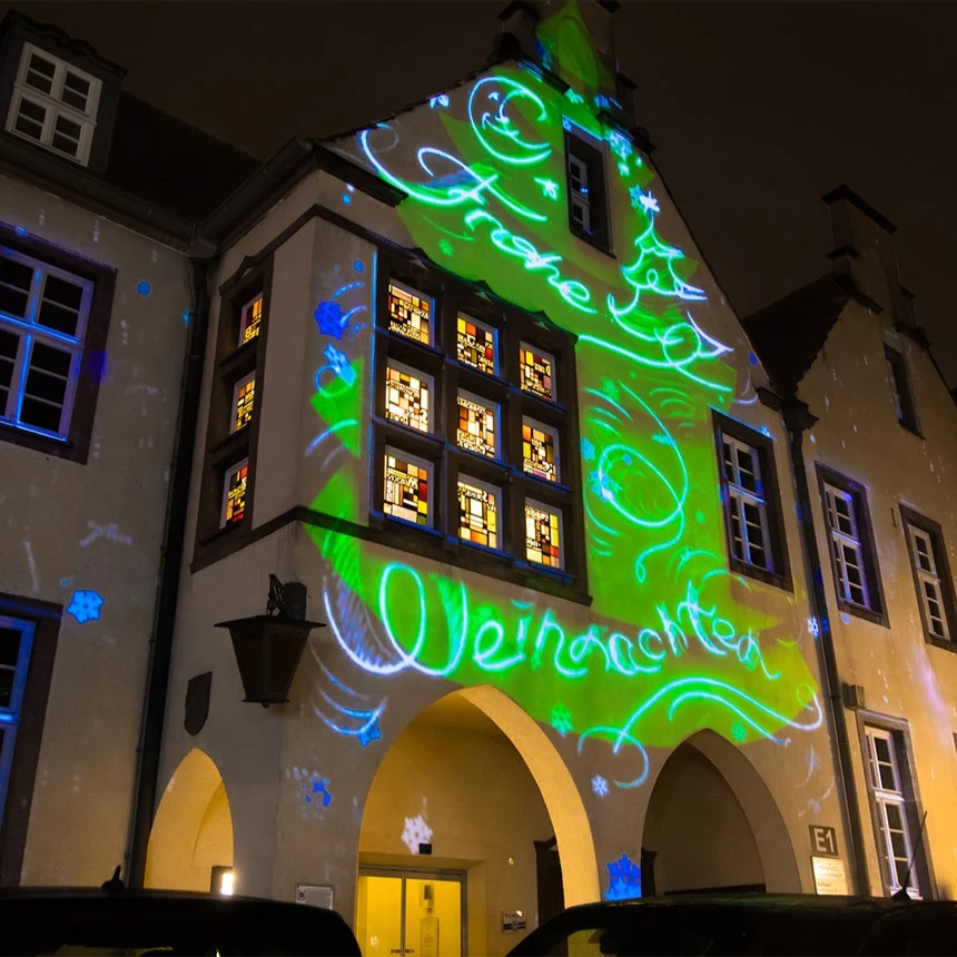 Facade projection of a virtual Christmas tree onto a historic town hall during Advent