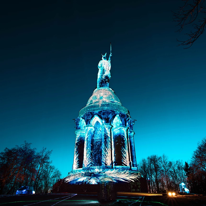 Hermannsdenkmal wird bei Abenddämmerung bunt beleuchtet