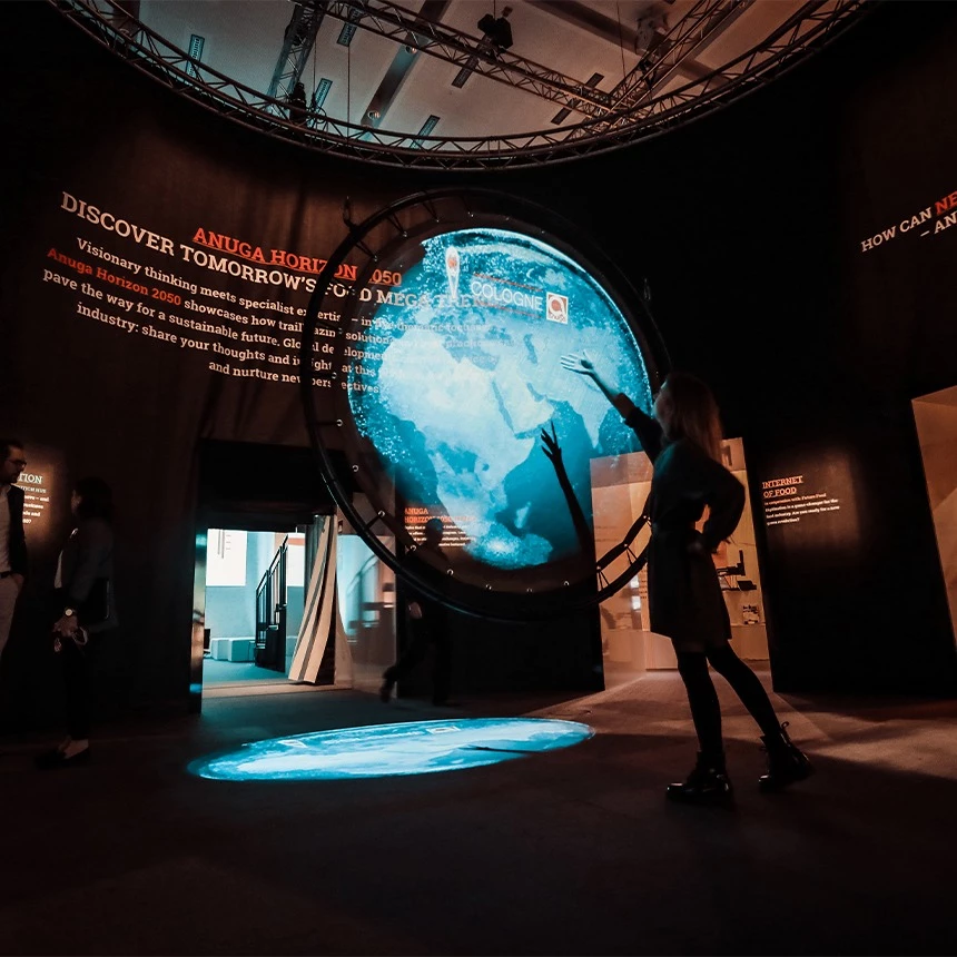 In the entrance area of an exhibition at the Anuga trade fair in Cologne, a visitor is shown in front of a hologram installation: the 3D projection shows a globe, which symbolizes global networking