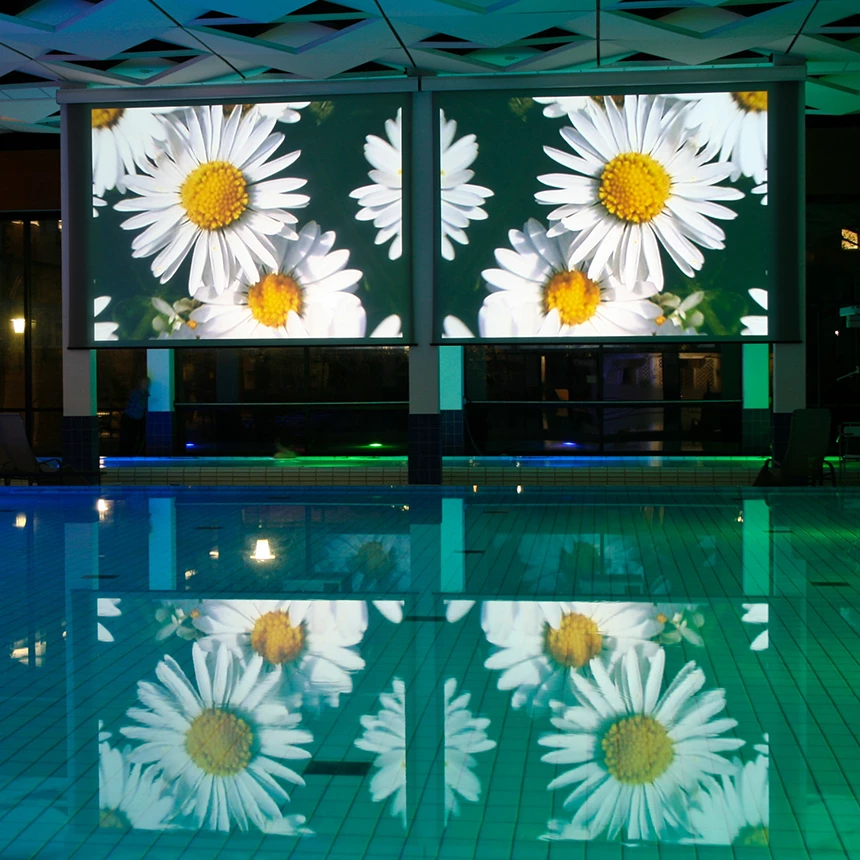 Daisies are projected onto two adjacent screens at the edge of the pool in a thermal bath