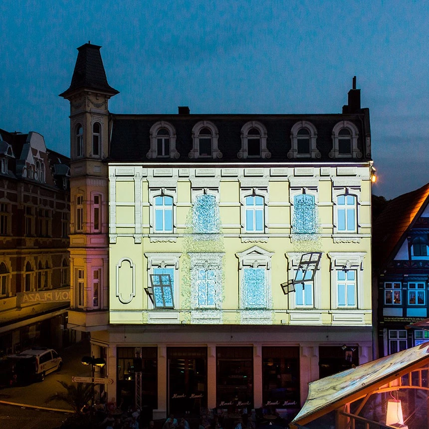 Bei einem 3D Video Mapping ist Wasser hinter den Fenstern eines Gebäudes zu sehen, einzelne Fenster sind gesprungen und das Wasser sucht sich seinen Weg ins Freie