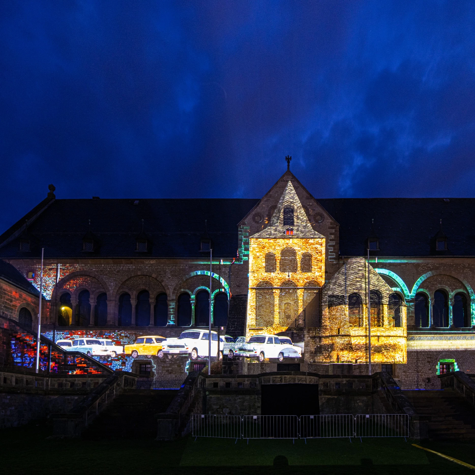 Bei einer Beamershow auf dem Gebäude der Kaiserpfalz erscheinen Trabbis, die durch das Breite Tor in Goslar fahren und somit die Stadt zur Wendezeit symbolisieren