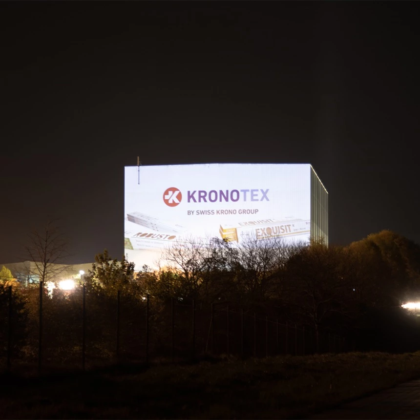 Videoprojektion als Leuchtwerbung mit Firmenlogo auf das Hochregallager von Swiss Krono