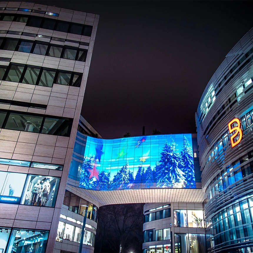 A Christmas illumination on the Düsseldorf Kö-Bogen shows colorful stars and shooting stars as well as a snow-covered pine forest