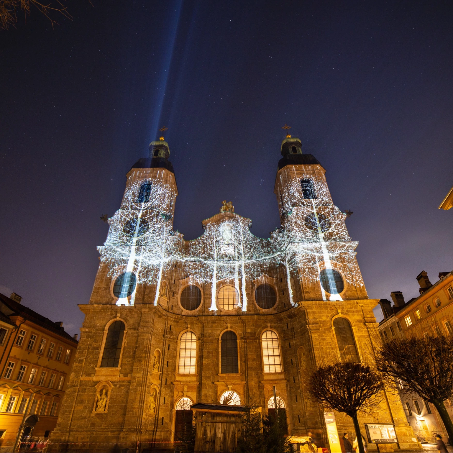 Während des Lichterspaziergangs zu Silvester in Innsbruck erscheint der Dom zu St. Jakob in neuem Licht: eine gebäudeindividuelle Fassadenprojektion zeigt Silhouetten von Bäumen in weiß