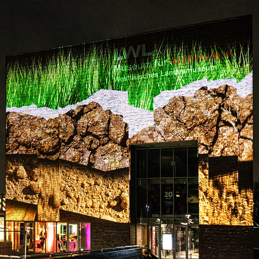 Large-scale facade projection shows earth and grass on the LWL Museum for Archeology and Culture in Herne