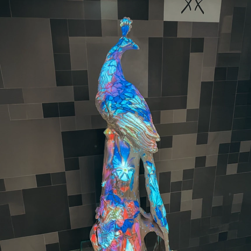 3D-Porzellan Skulptur eines Pfaus im Naturresort & Spa Schindelbruch inszeniert mit Videomapping, bei dem die Strukturen der Figur durch Videoprojektion hervorgehoben werden.