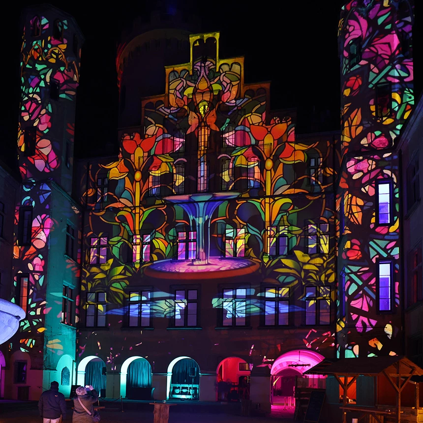 The facade of Arenfels Castle covered with a colorful floral pattern in a 3D video mapping