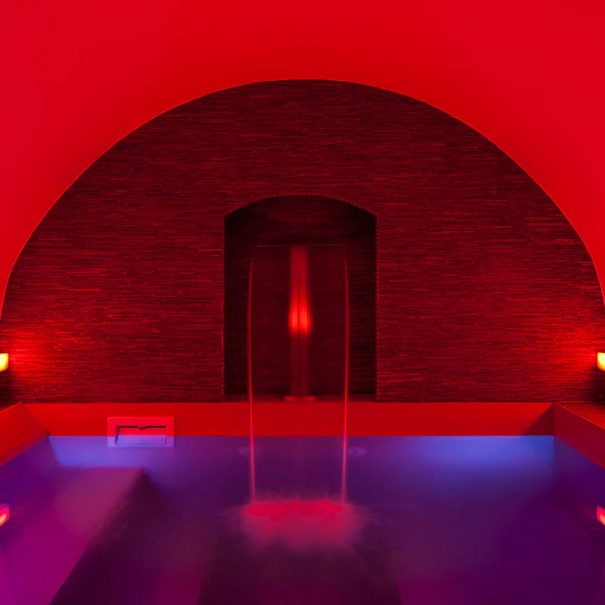 A wellness pool is bathed in red with atmospheric light