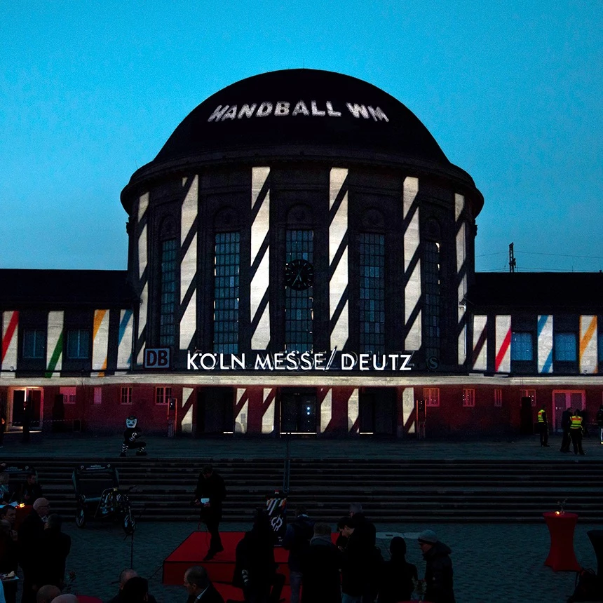 Gebäudeindividuelle Video-Projektion im Corporate Design der Handball WM legt sich wie eine zweite Haut über die Fassade des Bahnhofs Deutz in Köln