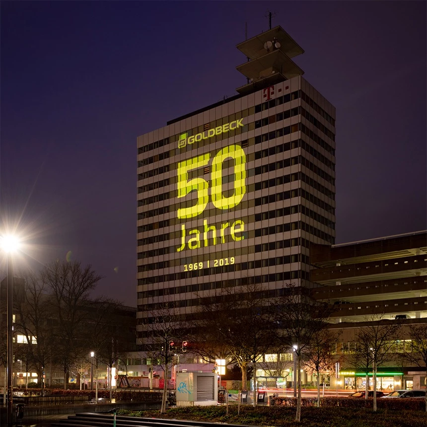 Großflächige Fassaden-Projektion auf Hochhaus in Innenstadt von Bielefeld zeigt Informationen zum Firmenjubläum von Goldbeck
