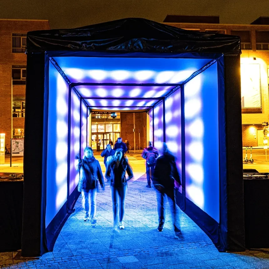 People walk through a blue light tunnel in downtown Wilhelmshaven