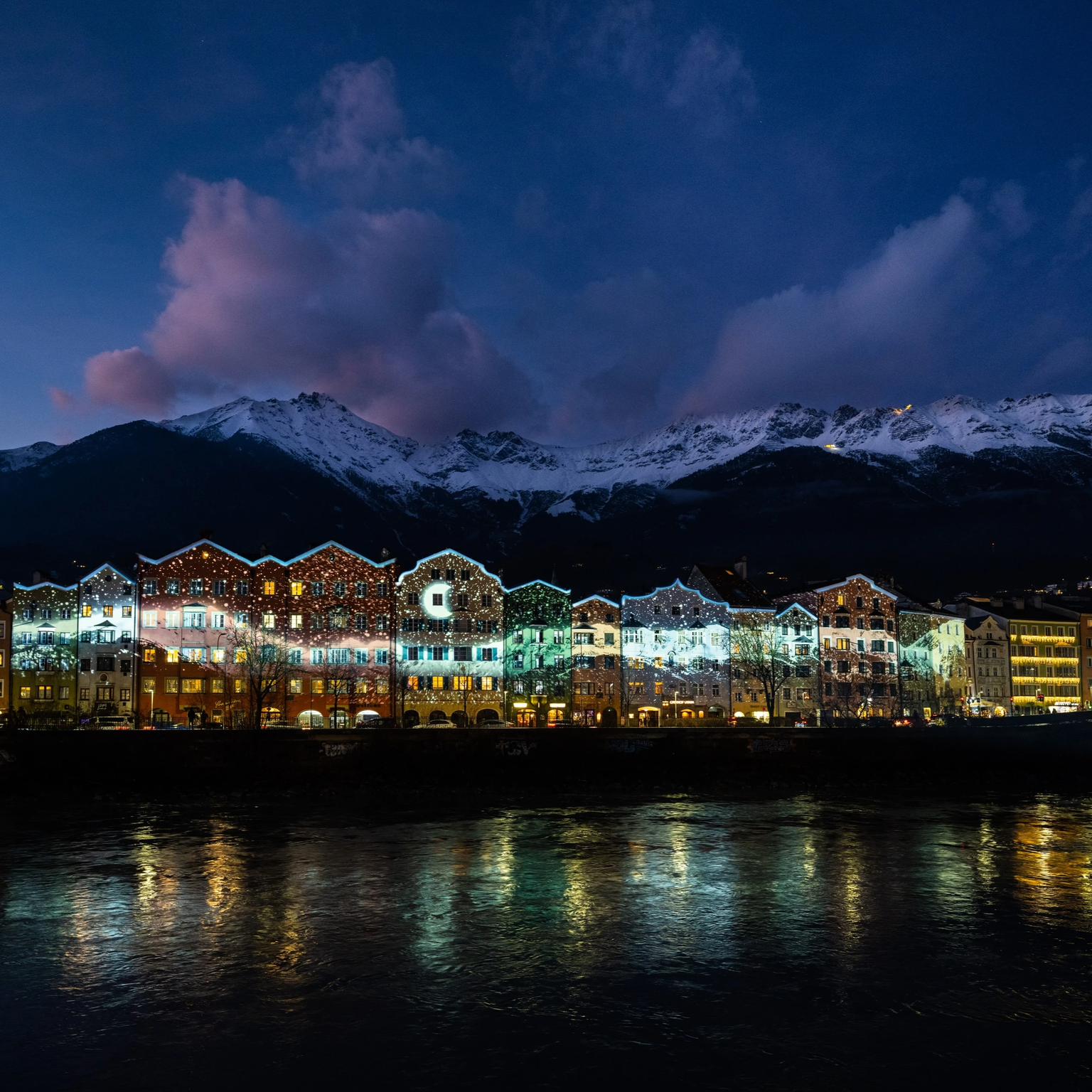The row of houses Mariahilf in Innsbruck is illuminated by light blue particles