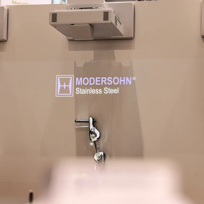 The company logo is projected onto the wall of a trade fair stand