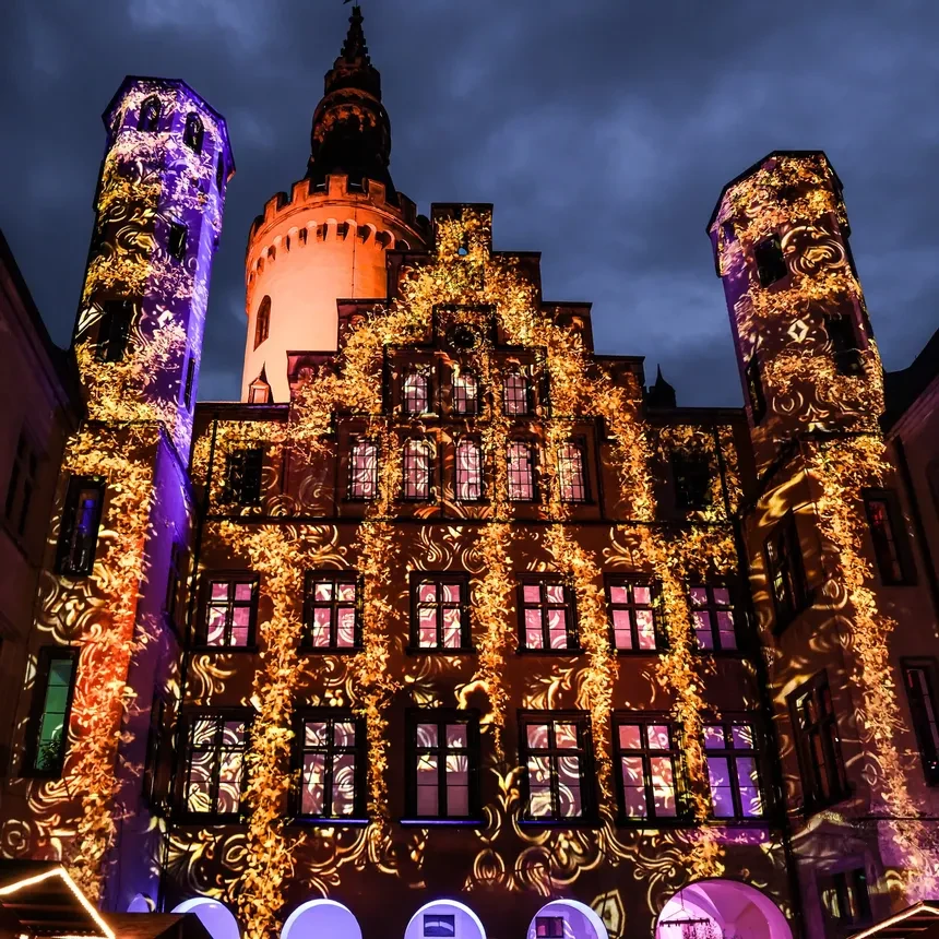 Flowers and golden ornaments twine virtually on the facade of Arenfeld Castle at a light festival