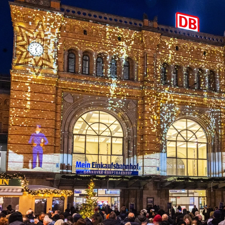 Visitors at the main train station in Hanover look at the facade, which is decorated with Christmas projections