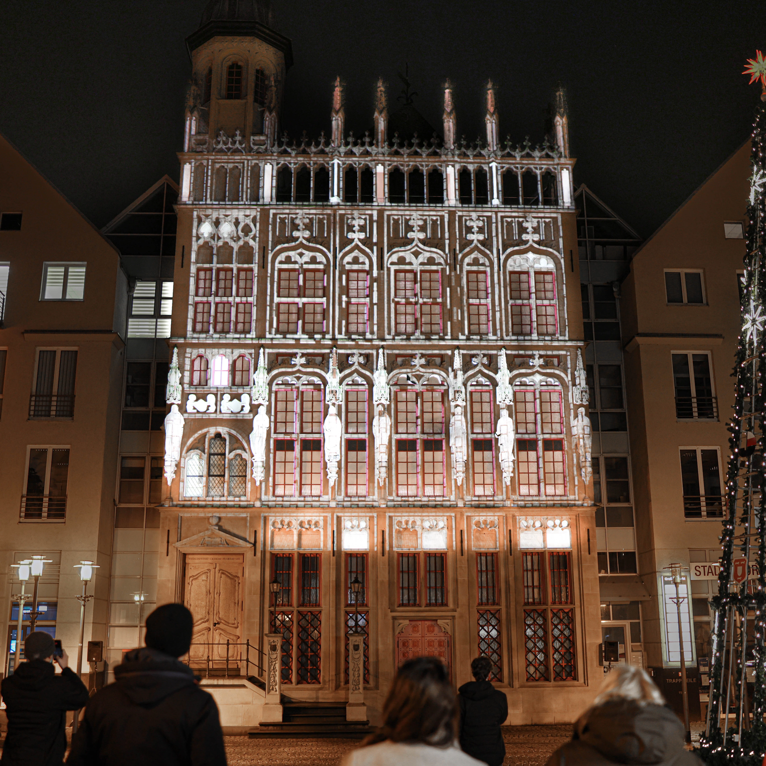 Video projection show on a Gothic facade with figure reliefs, ribbed vaults, pointed arches and buttresses shows 3D effects that are customized for each building