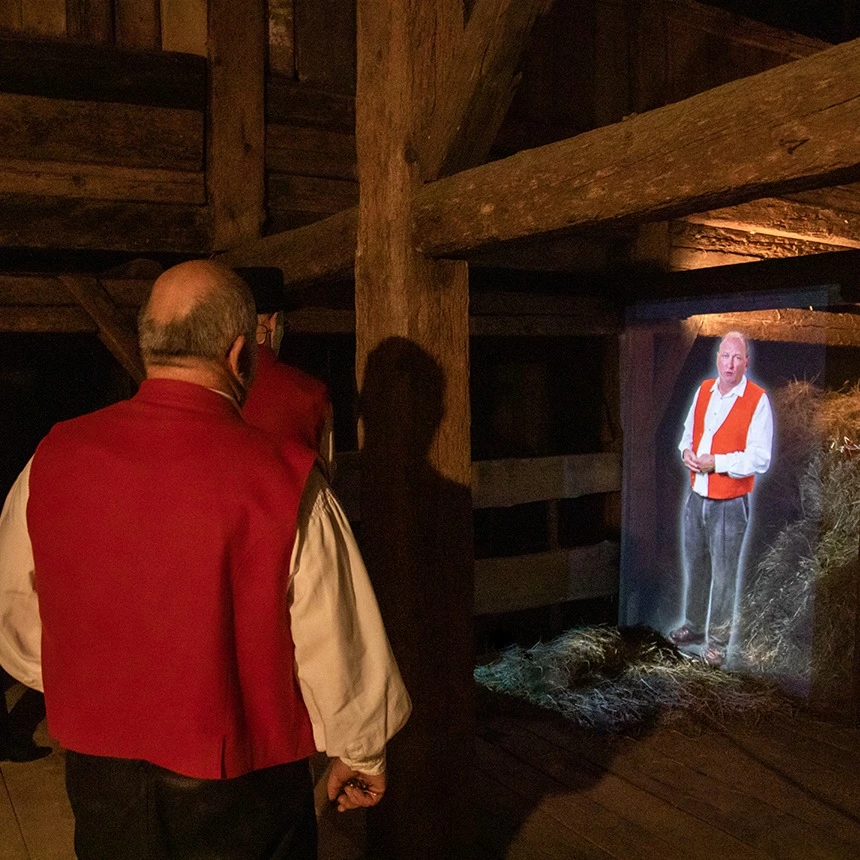 Projektion eines Knechts, der seine Lebensgeschichte erzählt: Die Figur erscheint als 3D Hologramm und fügt sich ganzheitlich in das historische Setting des Haldenhofs ein